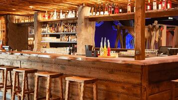Eine Bar mit Holzböden, die mit verschiedenen Flaschen gefüllt sind, einer Bar und hölzernen Barhocker.