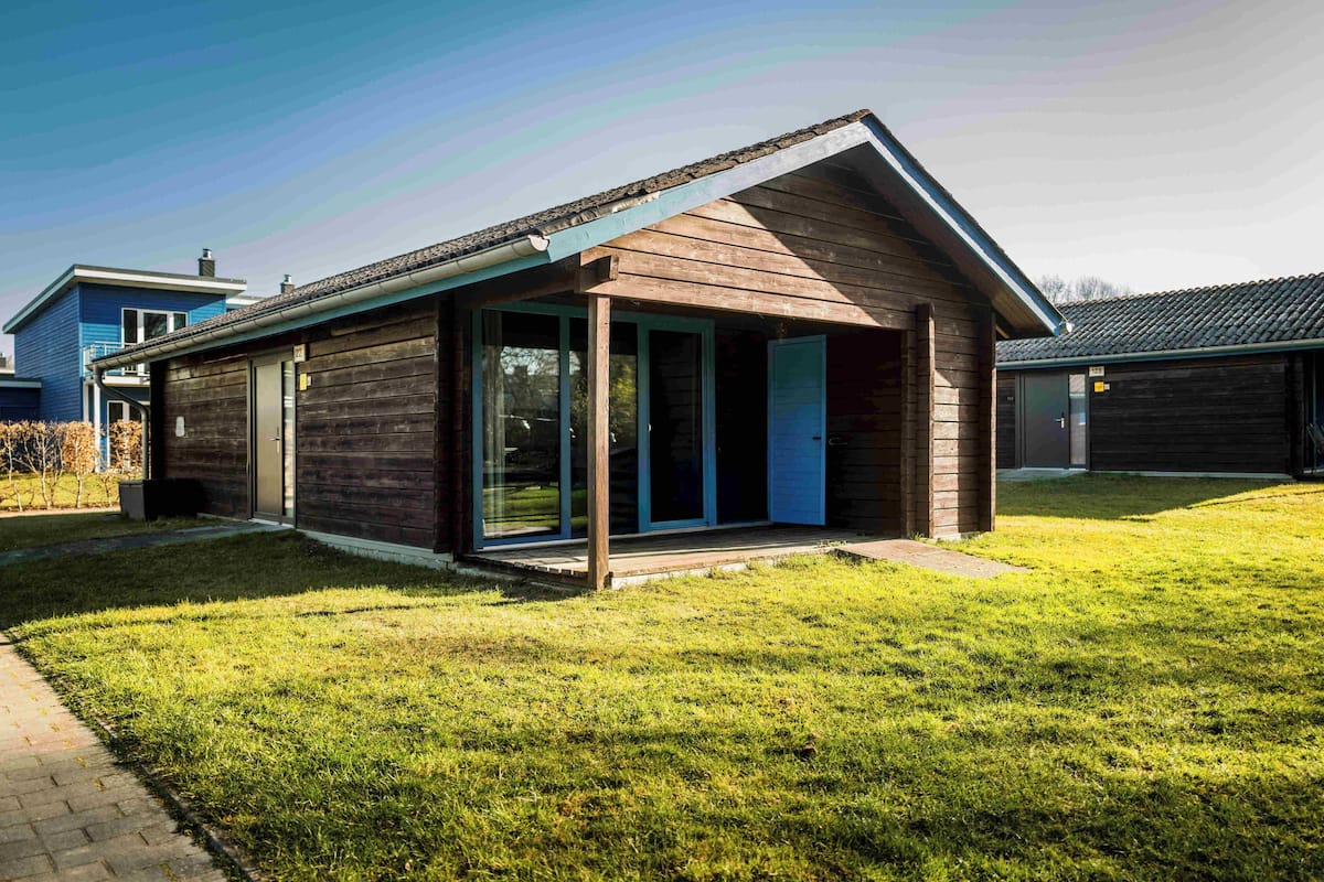 Una casa moderna con fachada de madera, puertas de cristal amplias y un porche cubierto.