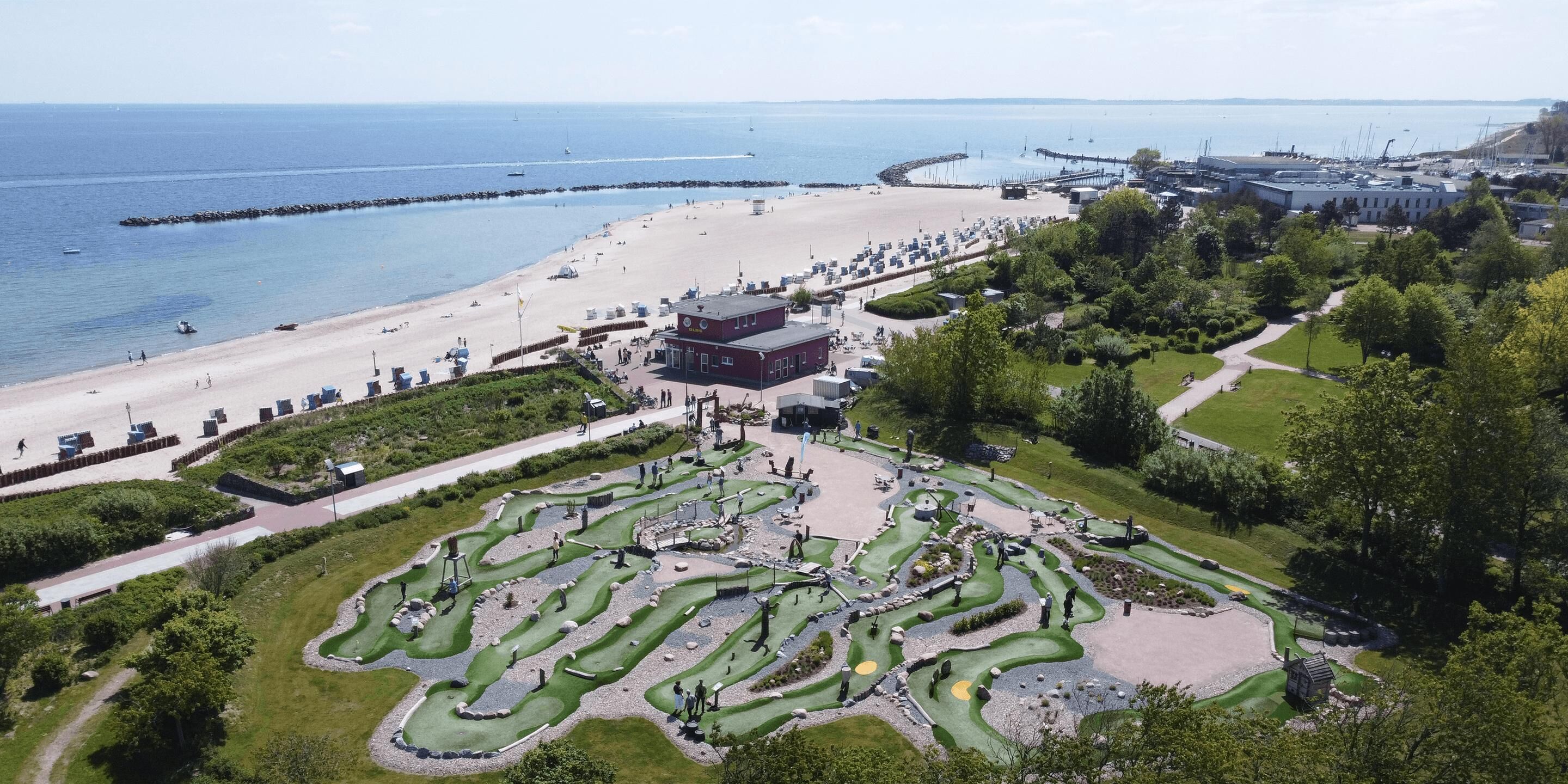 A golf course with a beach and marina in the background.