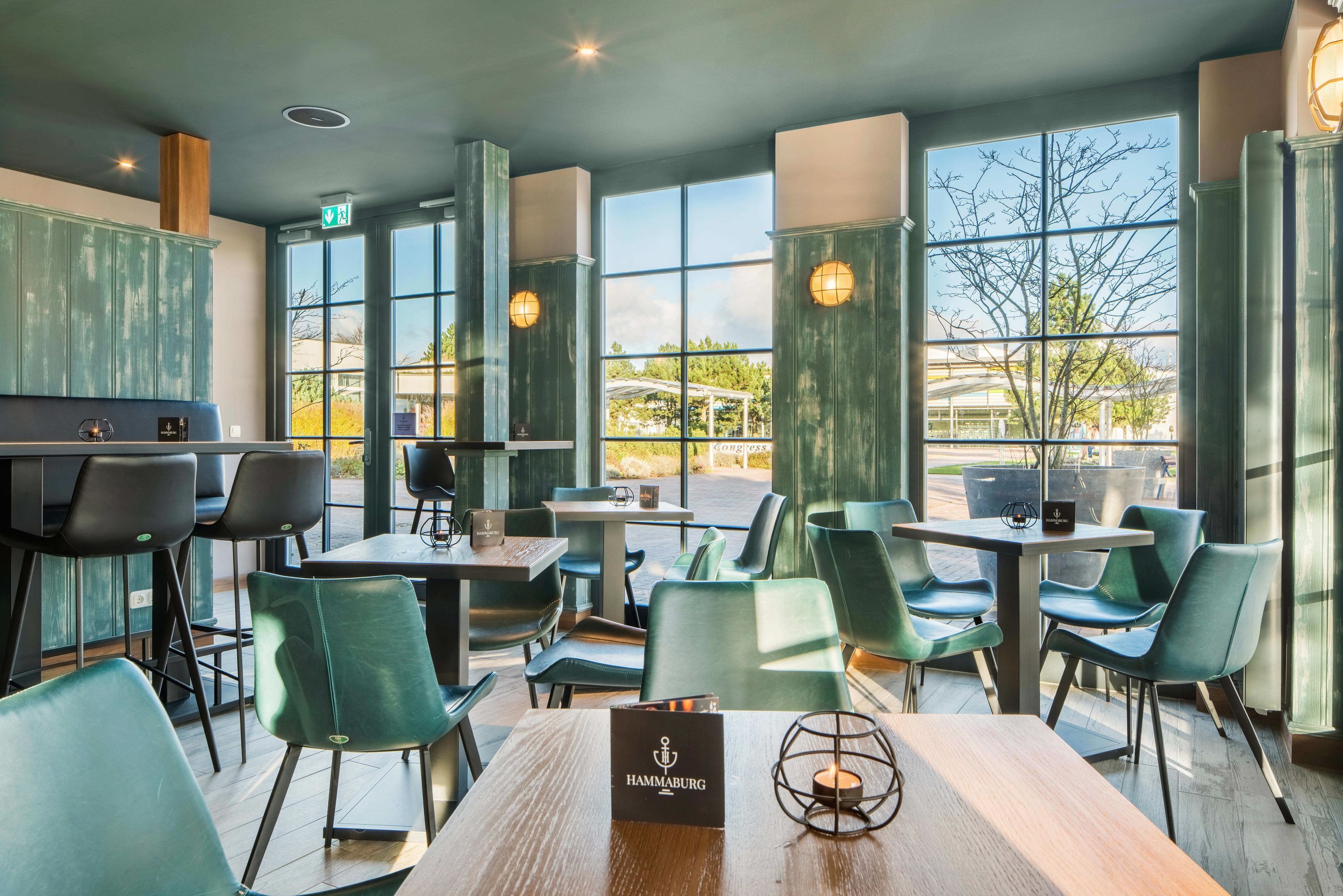 Un restaurant amb caires verds, taules de fusta i grans finestres que donen a l'exterior.