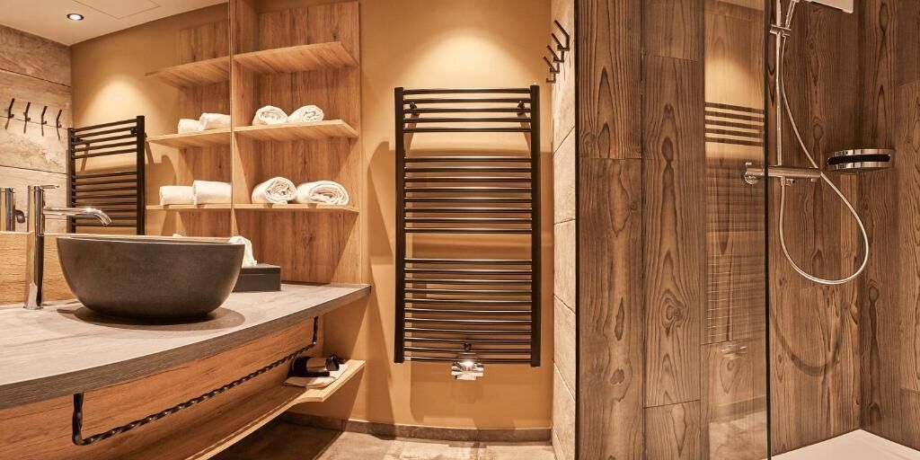A modern bathroom with a large bathtub, wooden shelves with towels, and a walk-in shower.