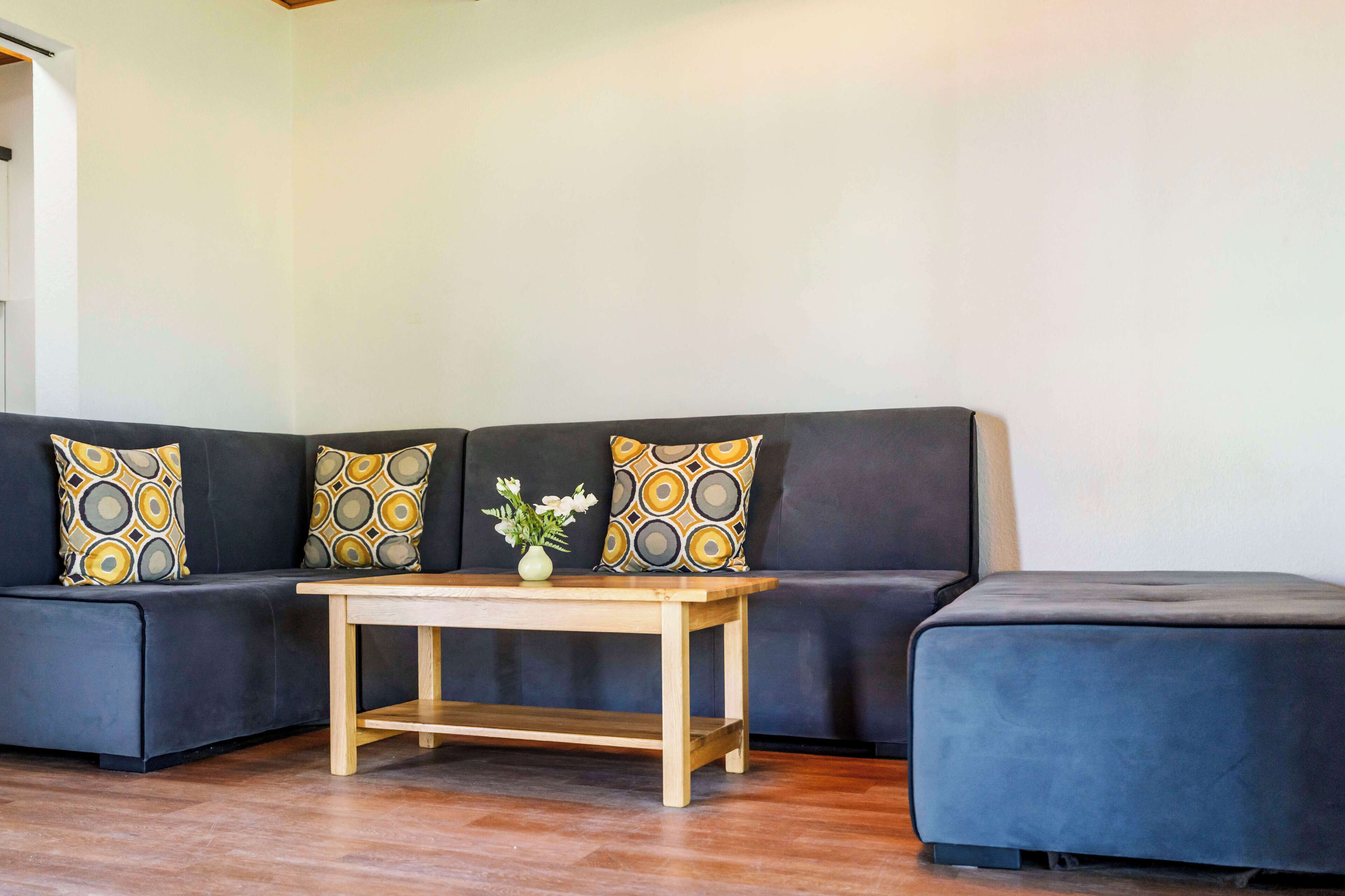 A living room with a dark-colored sofa, a wooden coffee table, and patterned cushions.