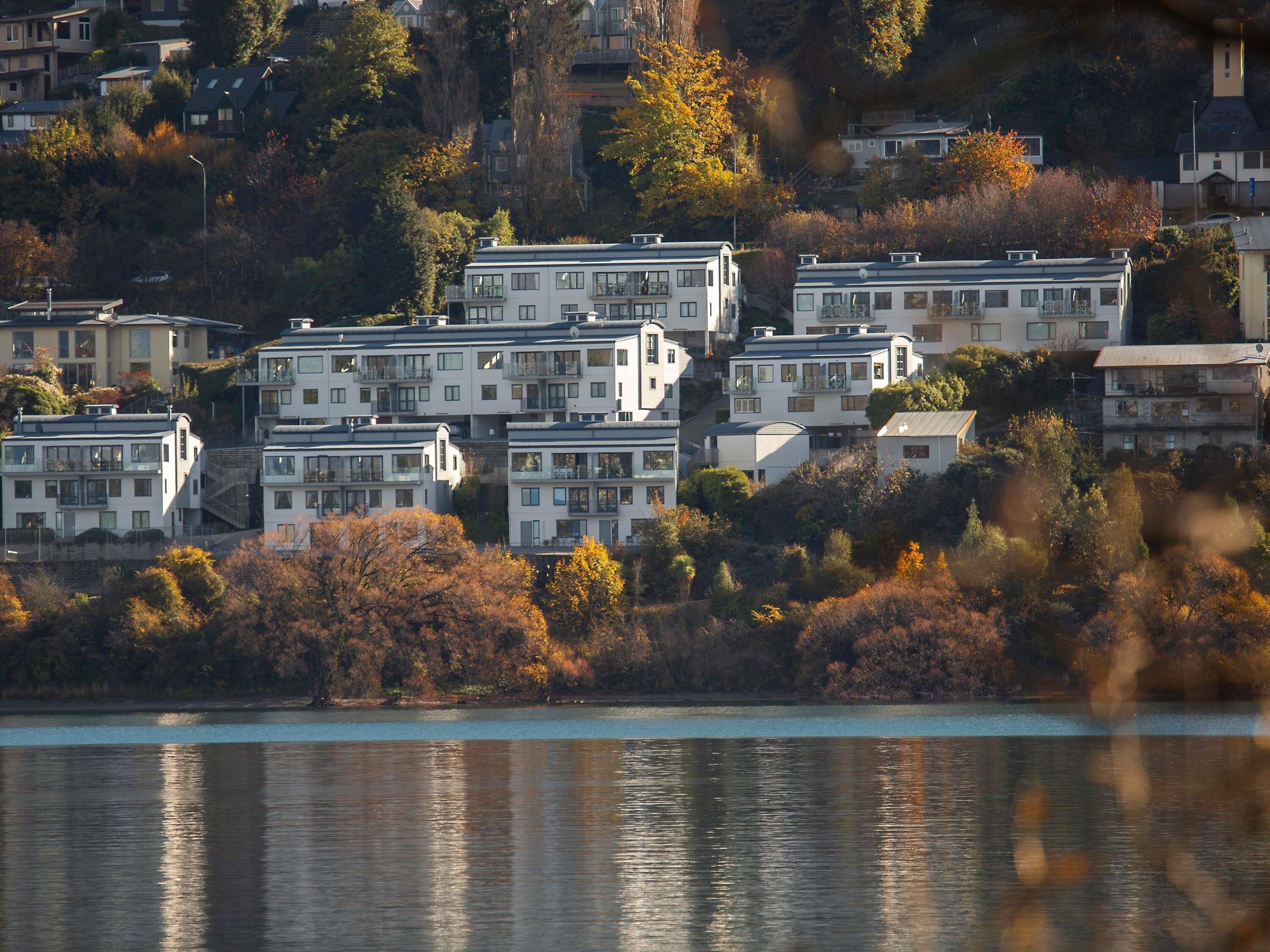 Un grup d'edificis moderns de diversos pisos amb balcons, situats en un turó amb vista a una massa d'aigua.