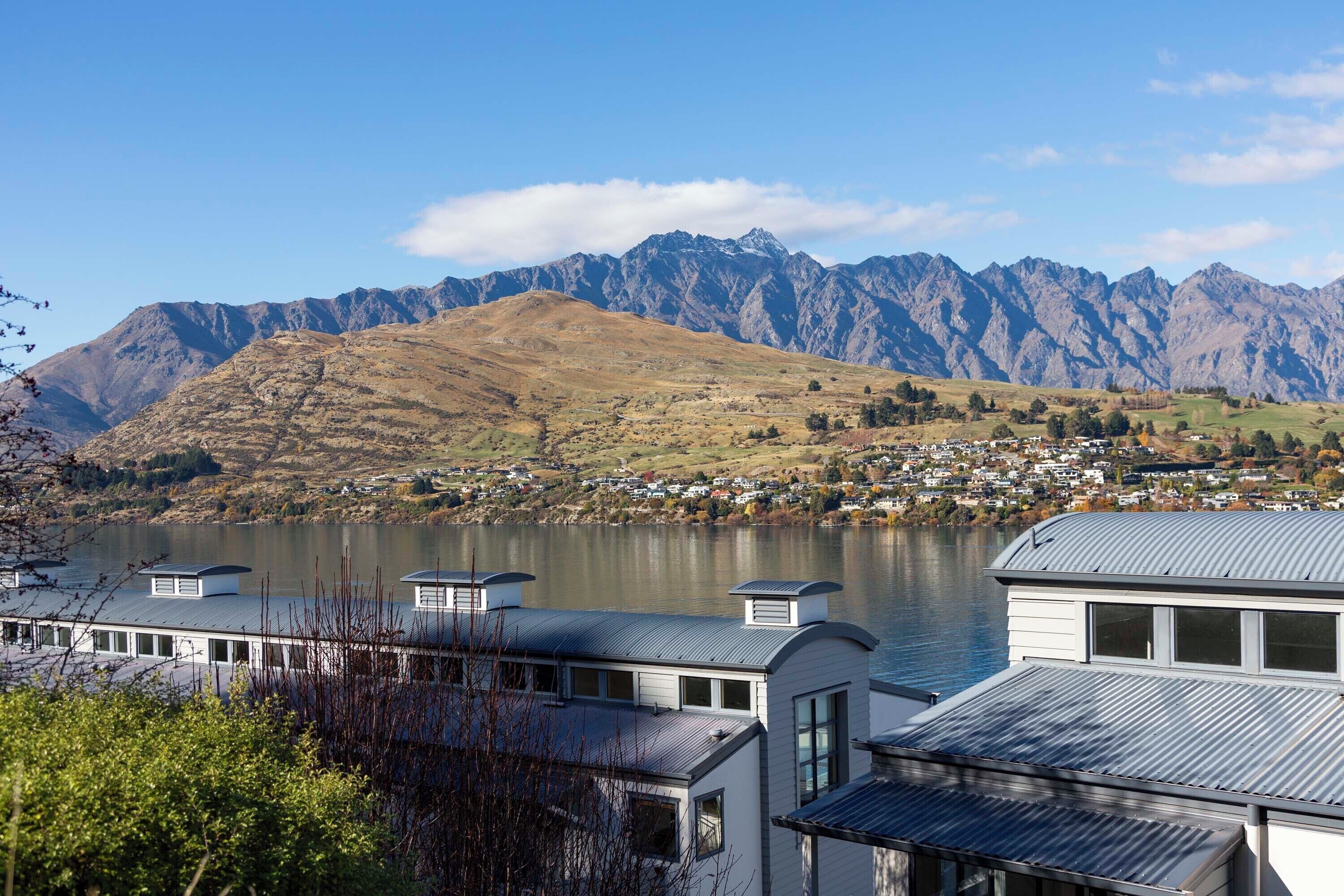 Hotel na beira do lago com vista para montanhas e uma cidade pequena ao fundo.