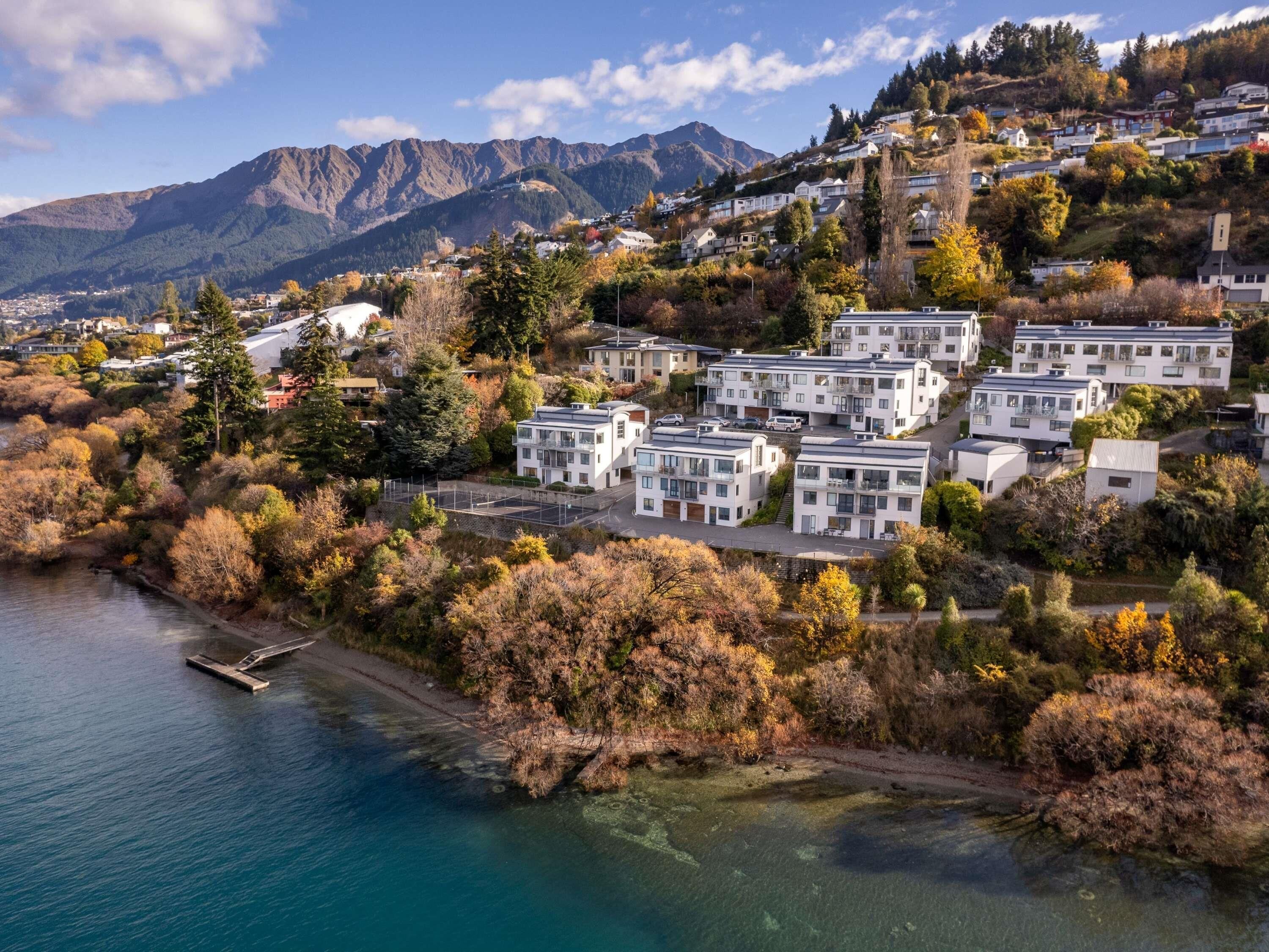 A residential area with modern houses, a clear view of the surrounding mountains, and a body of water.