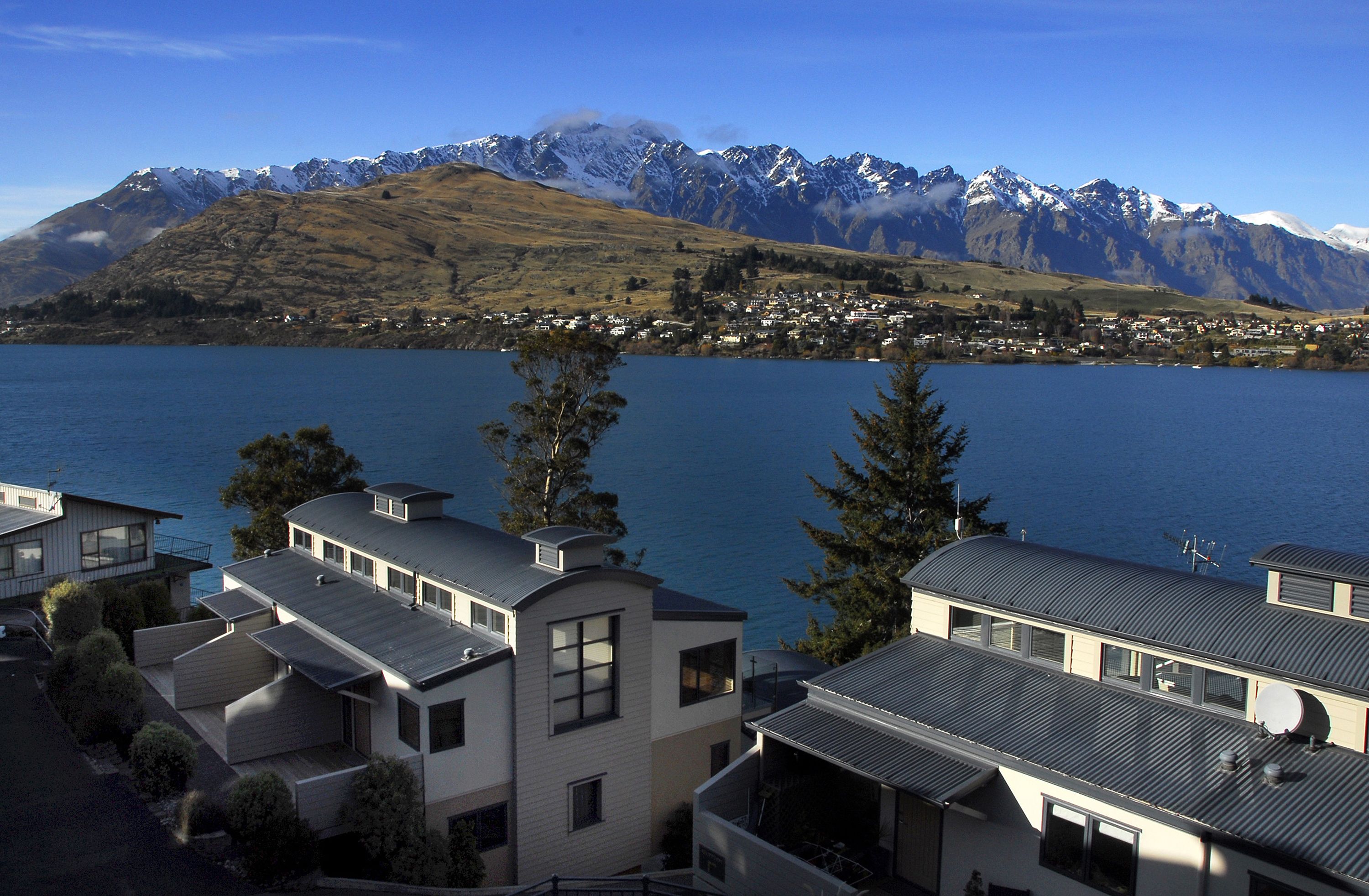 A residential area with modern houses, a lake, and a mountain range in the background.