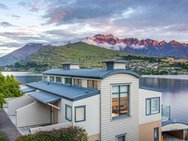A modern house with a large bay window, a flat roof, and a view of mountains and a lake.