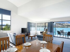 A dining area with a table set for four, a television, and a sofa.
