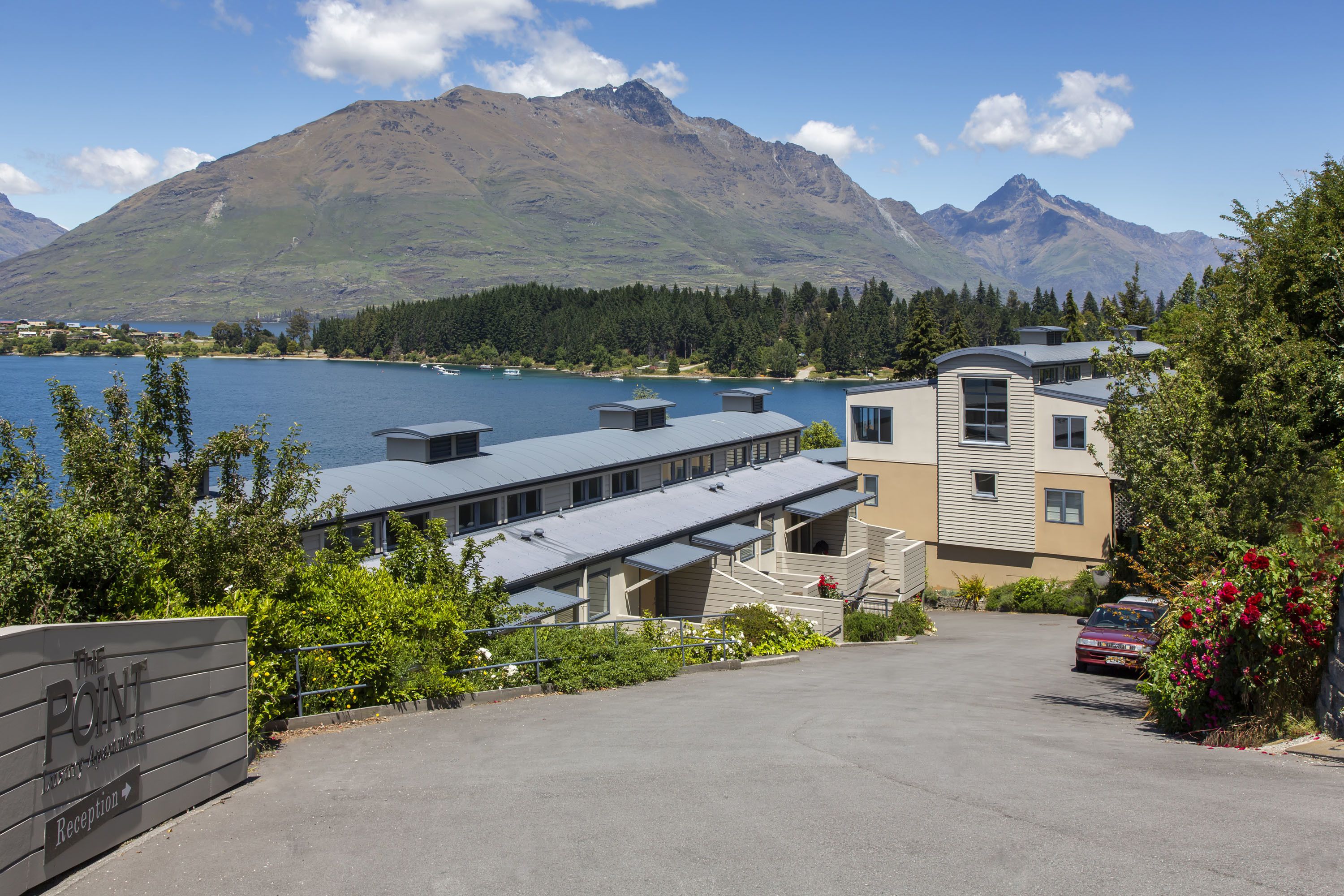 Un hotel con recepción, aparcamiento y vistas a un lago y montañas.