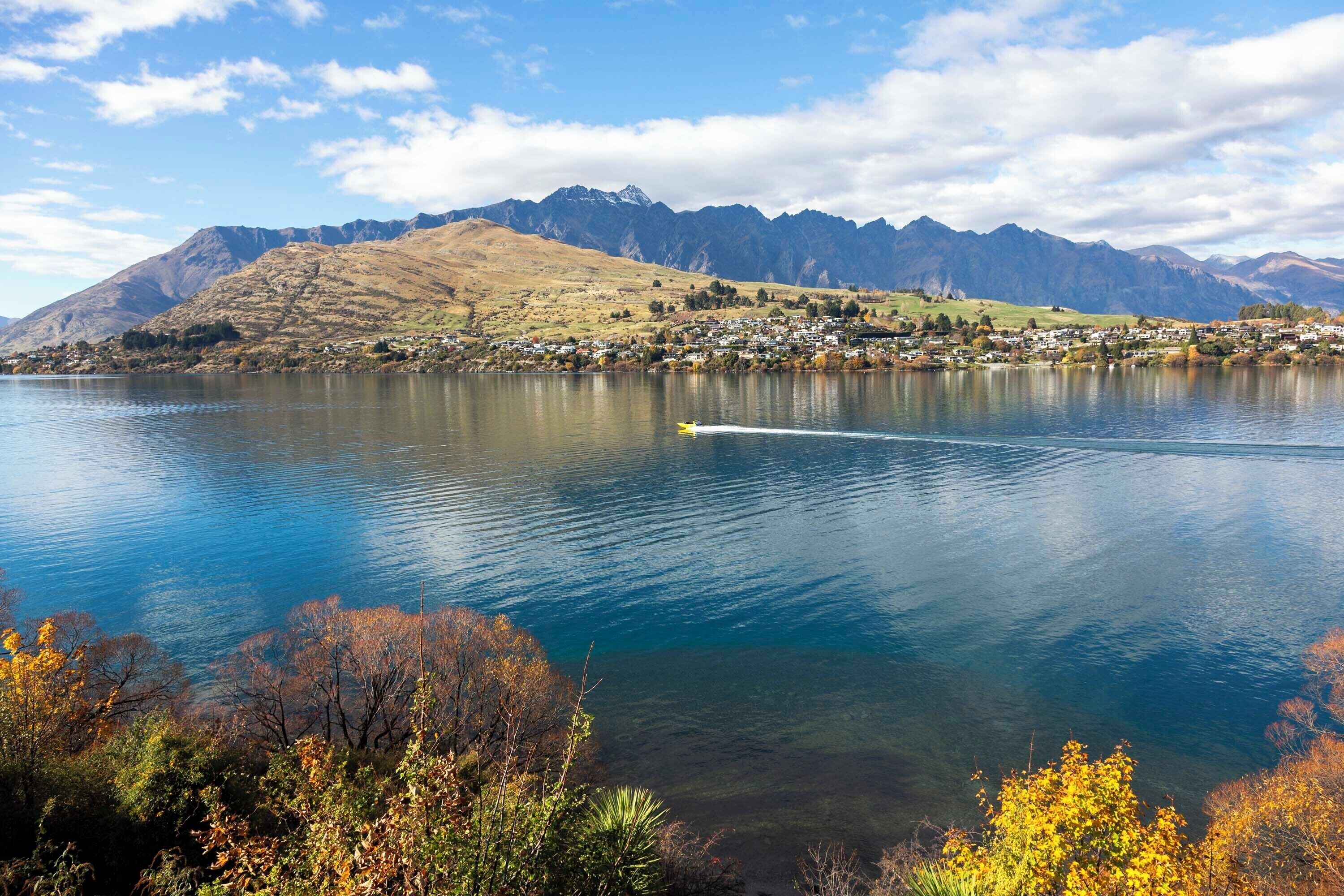 Een meer met bergen op de achtergrond en een klein stadje aan de overkant van het water.