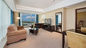 Une chambre d’hôtel avec une grande fenêtre, un canapé, une table basse, une télévision et un miroir.