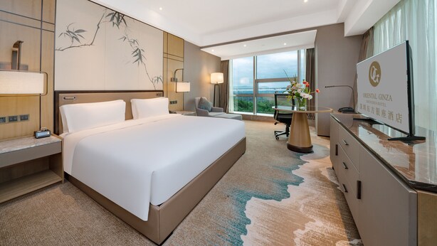 Une chambre d’hôtel moderne, dotée d’un grand lit, d’un bureau et d’une télévision.