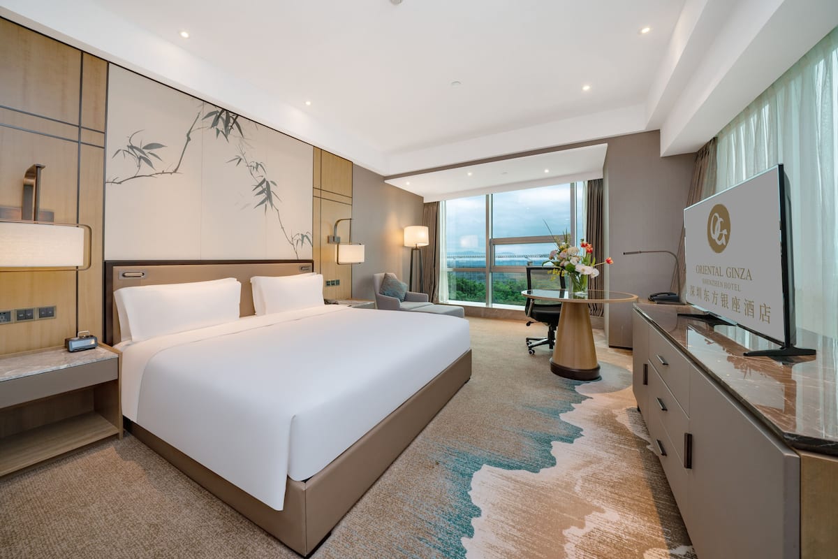 A modern hotel room with a large bed, a desk, and a television.
