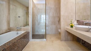 Une salle de bain moderne dotée d’une douche à parois de verre, d’une baignoire sur pieds et d’un meuble-lavabo avec un évier et un miroir.