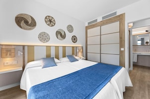 A hotel room with a large bed, bedside tables, a mirror, and wall decorations.