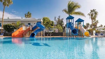 Ein Pool mit mehreren Wasserrutschen, Palmen und Liegestühlen.