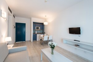 Una sala de estar moderna con un sofá, una mesa de centro y un televisor montado en la pared.