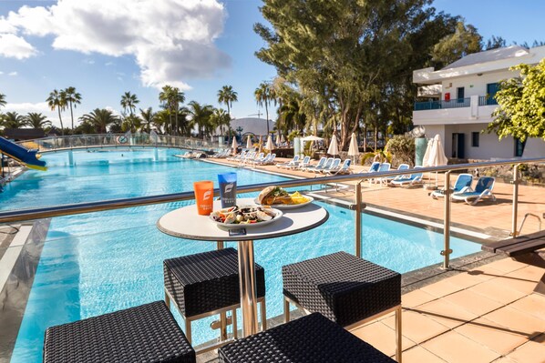 Ein Poolbereich mit Liegestühlen, einem Tisch mit Speisen und einem Pool.