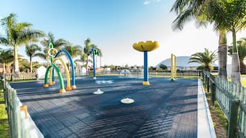 A playground with colorful play structures and palm trees.