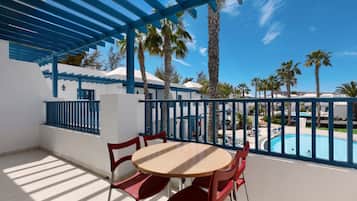 A terrace with a pool view, red chairs, and a blue pergola.
