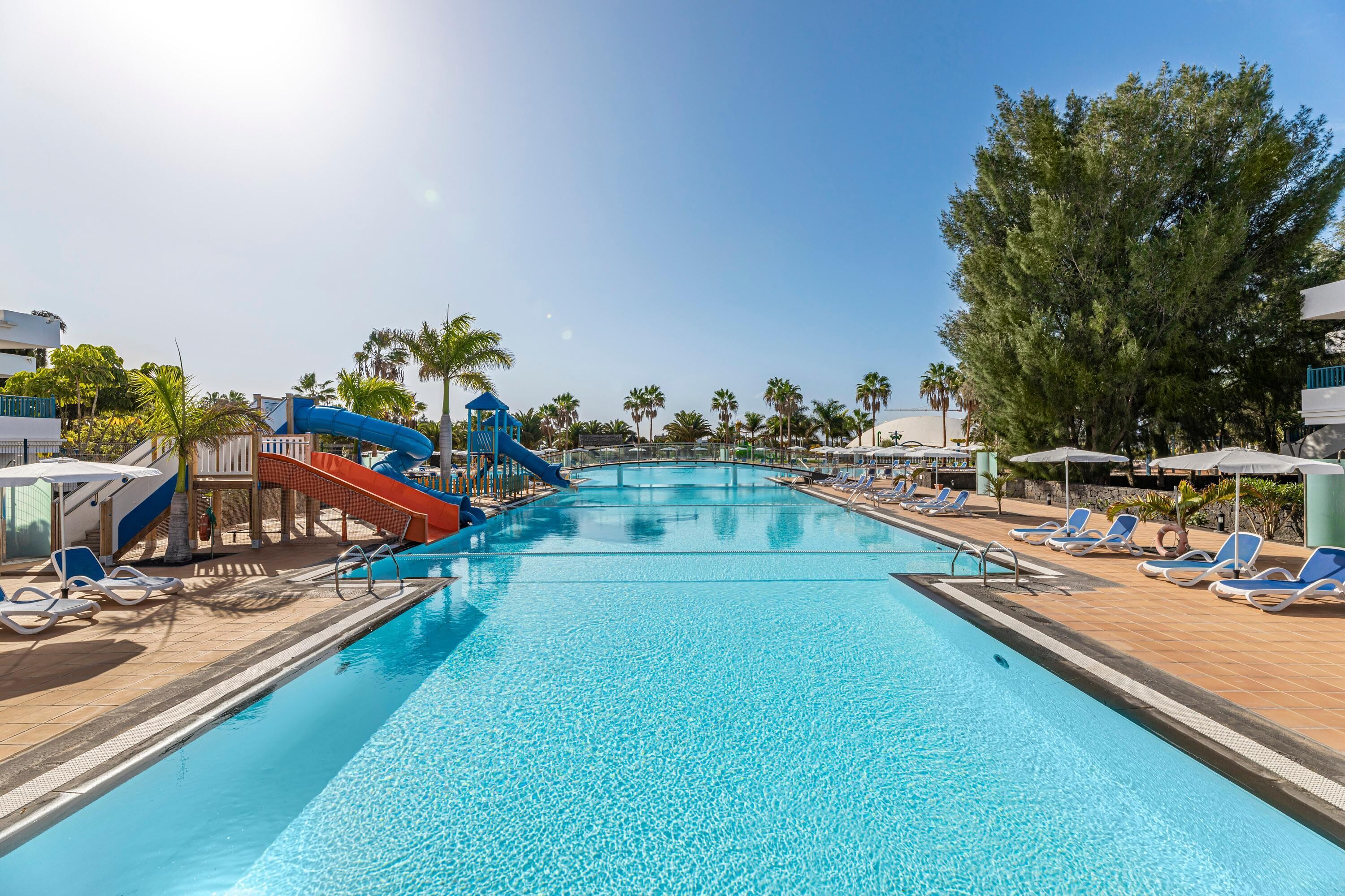 A swimming pool with slides and lounge chairs.