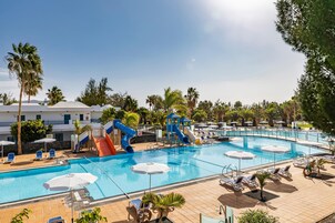 Una piscina con toboganes, tumbonas y sombrillas.