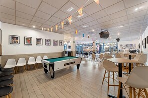 A pool table with chairs, a dining area with tables and chairs, and framed pictures on the walls. - THB Tropical Island Aparthotel (Yaiza)