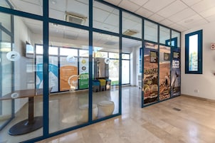Un interior moderno con divisiones de vidrio, una mesa de recepción y carteles informativos.