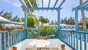 A covered outdoor seating area with a round table and two chairs, surrounded by a blue railing and palm trees in the background. - THB Tropical Island Aparthotel (Yaiza)
