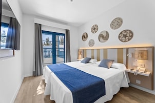 Una habitación de hotel moderna con dos camas, un ventanal con cortinas y decoración en la pared.