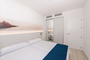 A hotel room with a bed, a mirror, a wardrobe, and a wall-mounted artwork. - THB Tropical Island Aparthotel (Yaiza)