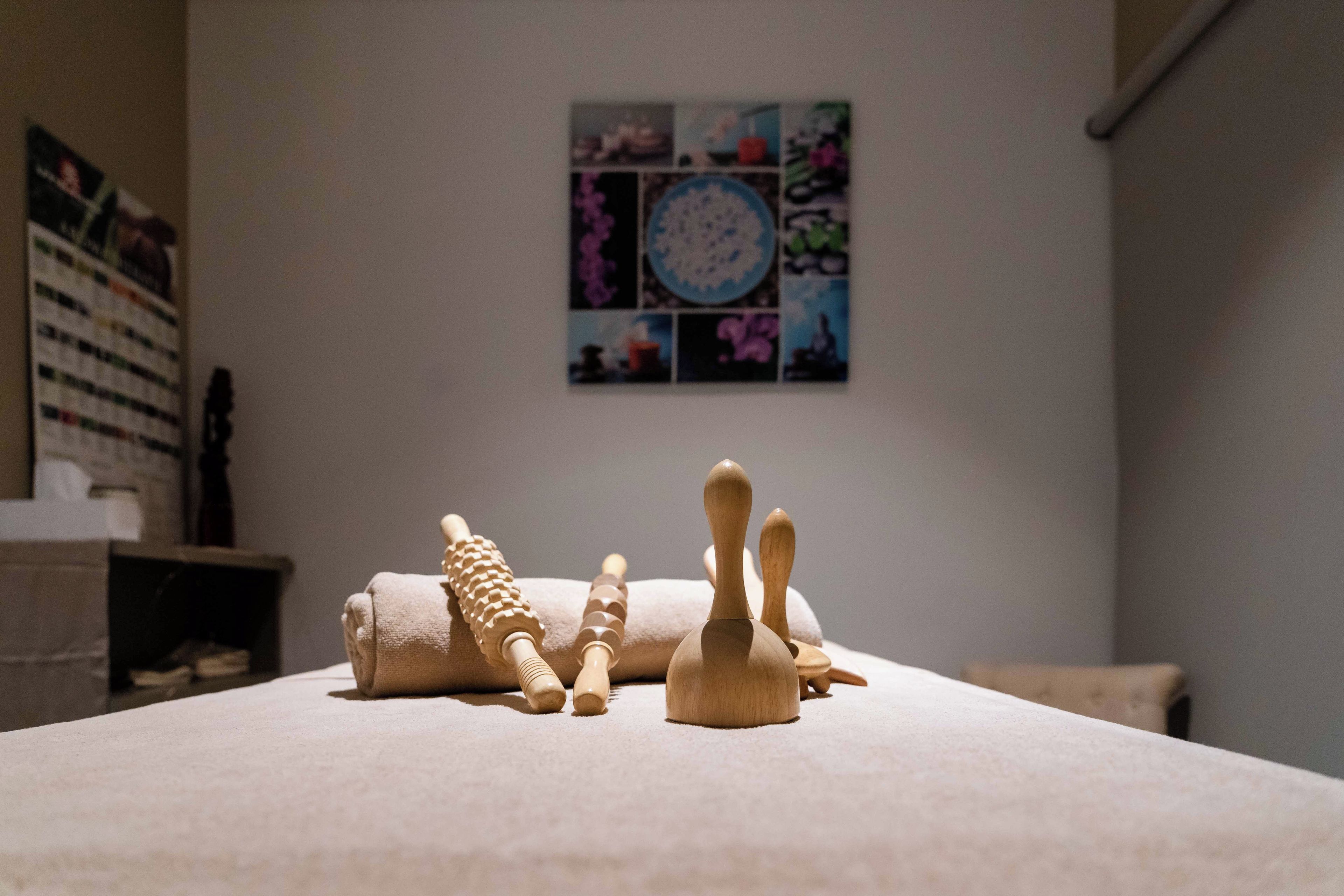 Una habitación con una cama, una mesita con objetos de madera y una pared decorada con un collage de imágenes.