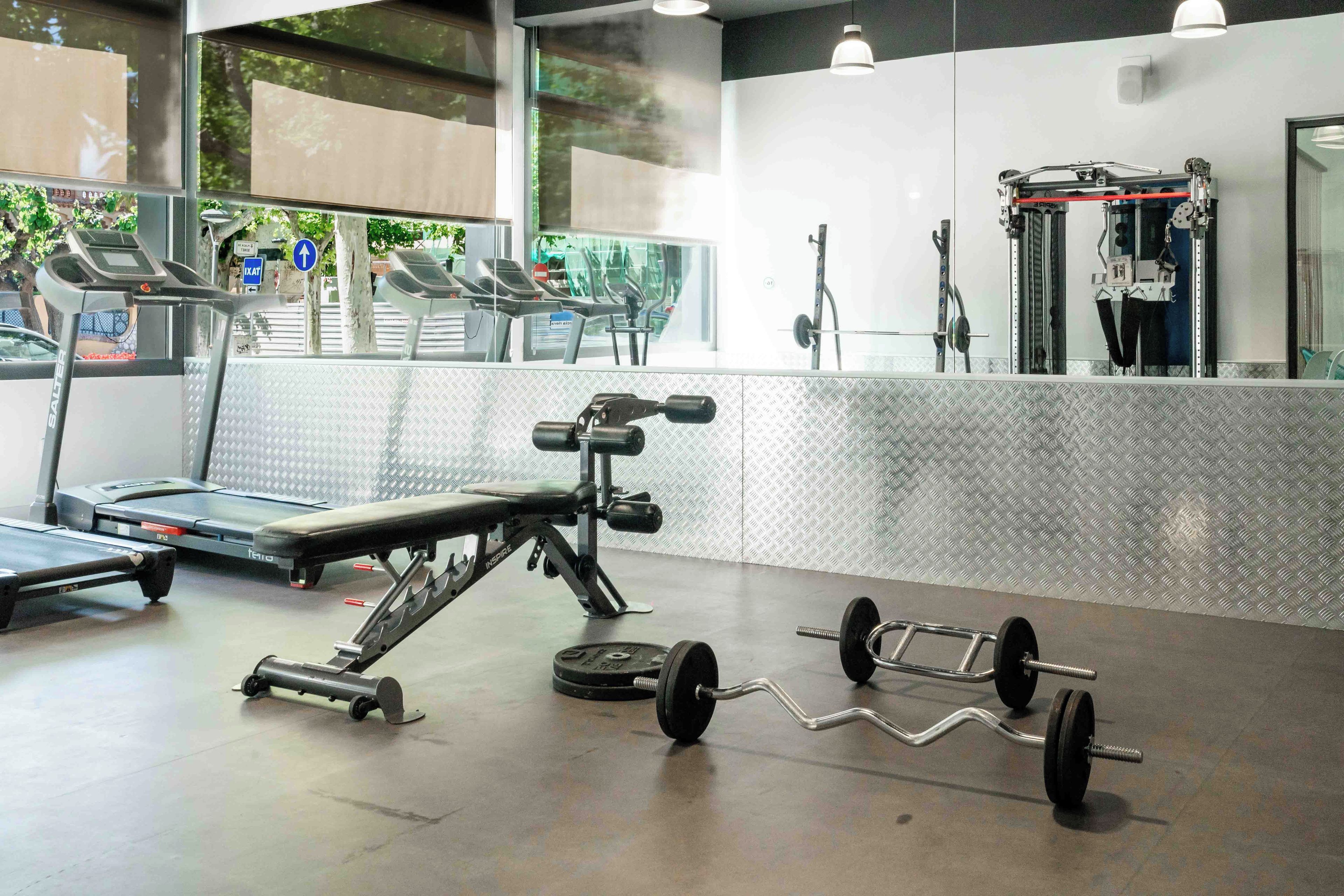 Une salle de sport équipée de tapis de course, d’un banc de développé couché et d’un support à squats.