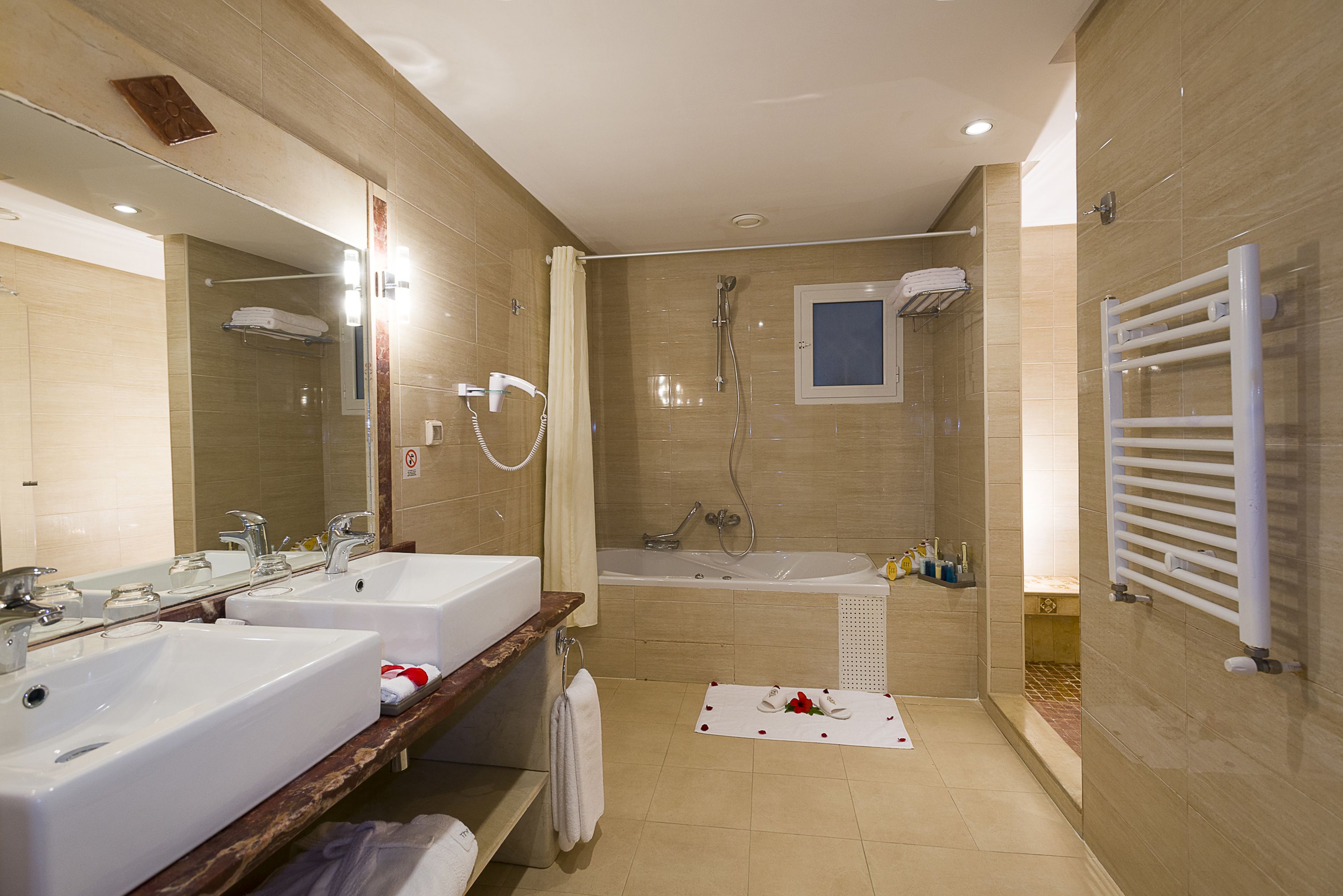 Un baño moderno con dos lavamanos, una bañera y una ducha.
