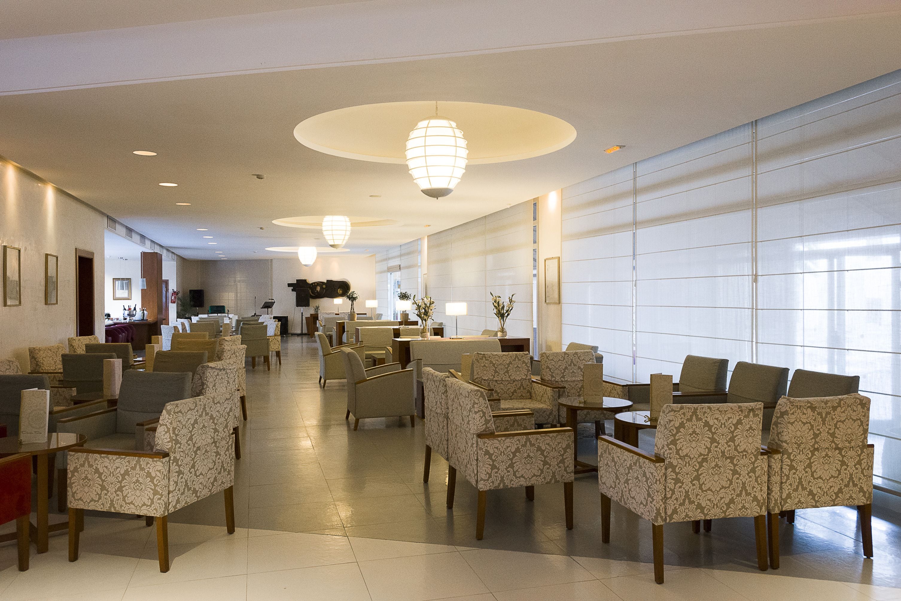 A spacious lobby with patterned chairs and tables, a reception area, and large windows allowing natural light.