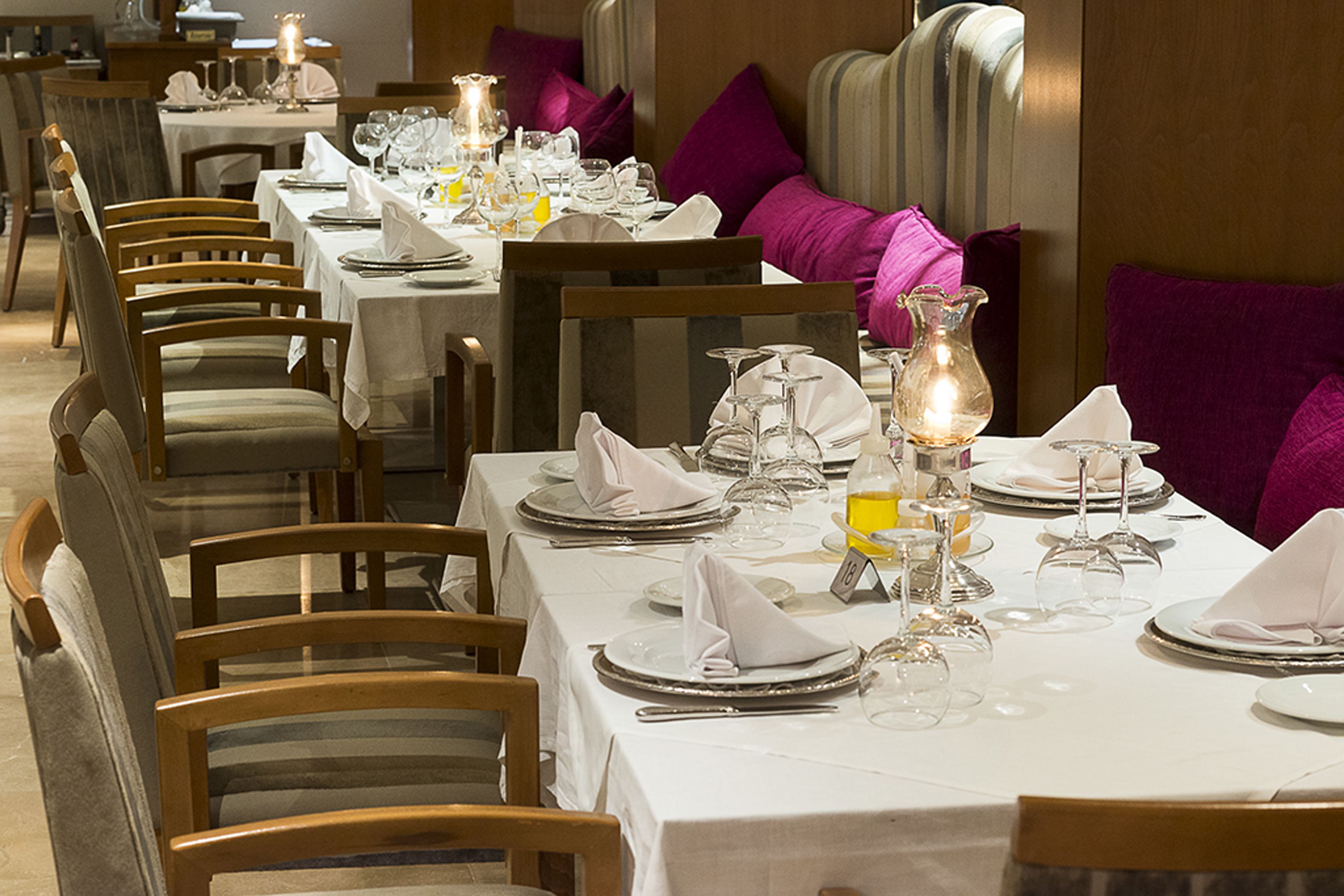 A restaurant with multiple tables set for dining, each with chairs and neatly arranged table settings.