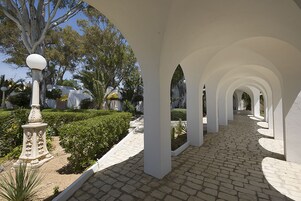 Un paseo techado con columnas blancas y un camino adoquinado.