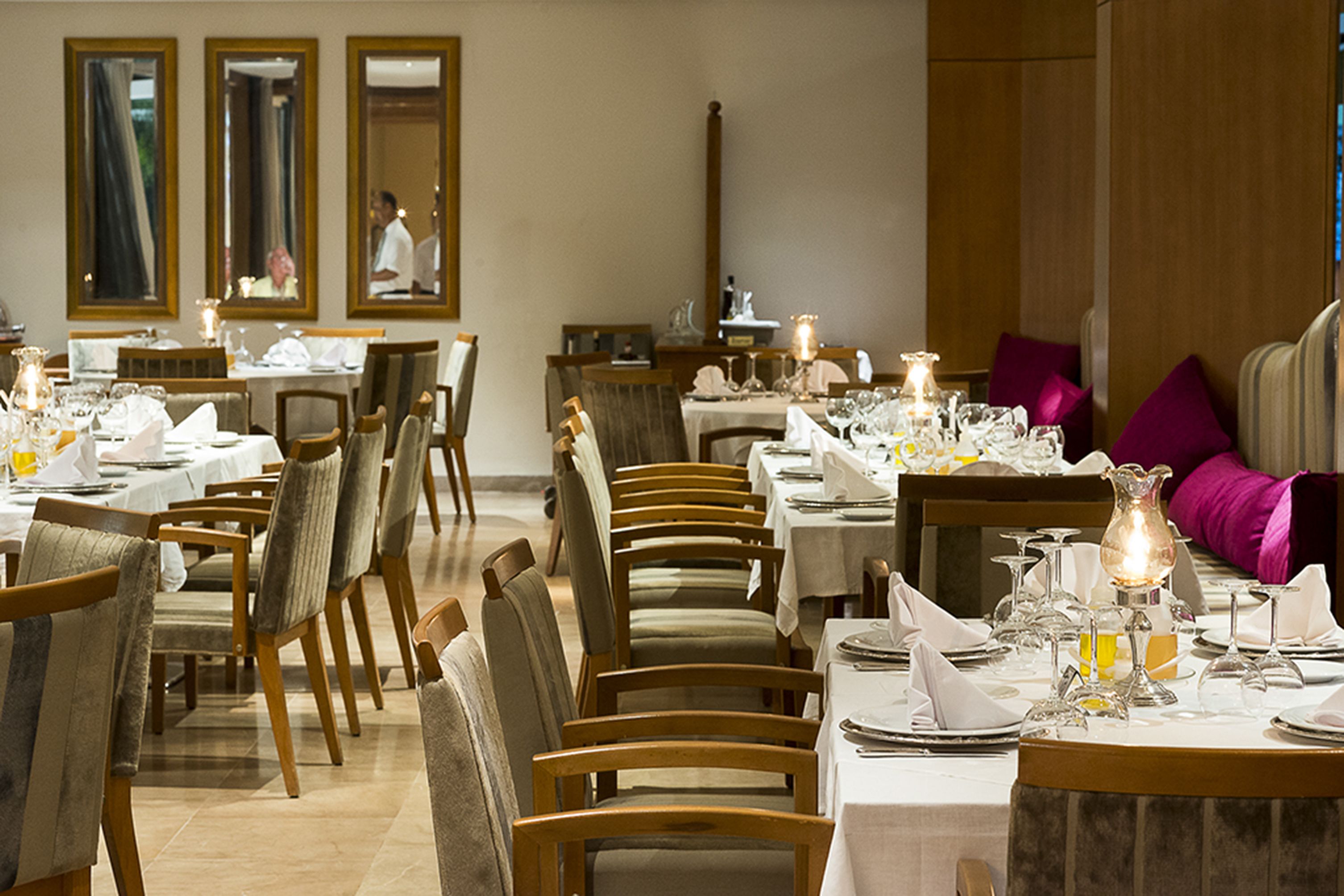 A dining area with multiple tables set for service, wooden chairs, and a modern interior design.