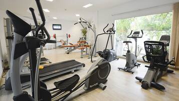 A gym with various exercise equipment including treadmills, stationary bikes, and elliptical machines.