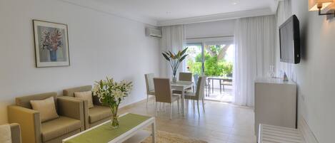 A modern living room with a sofa set, a coffee table, and a dining area with chairs and a table.