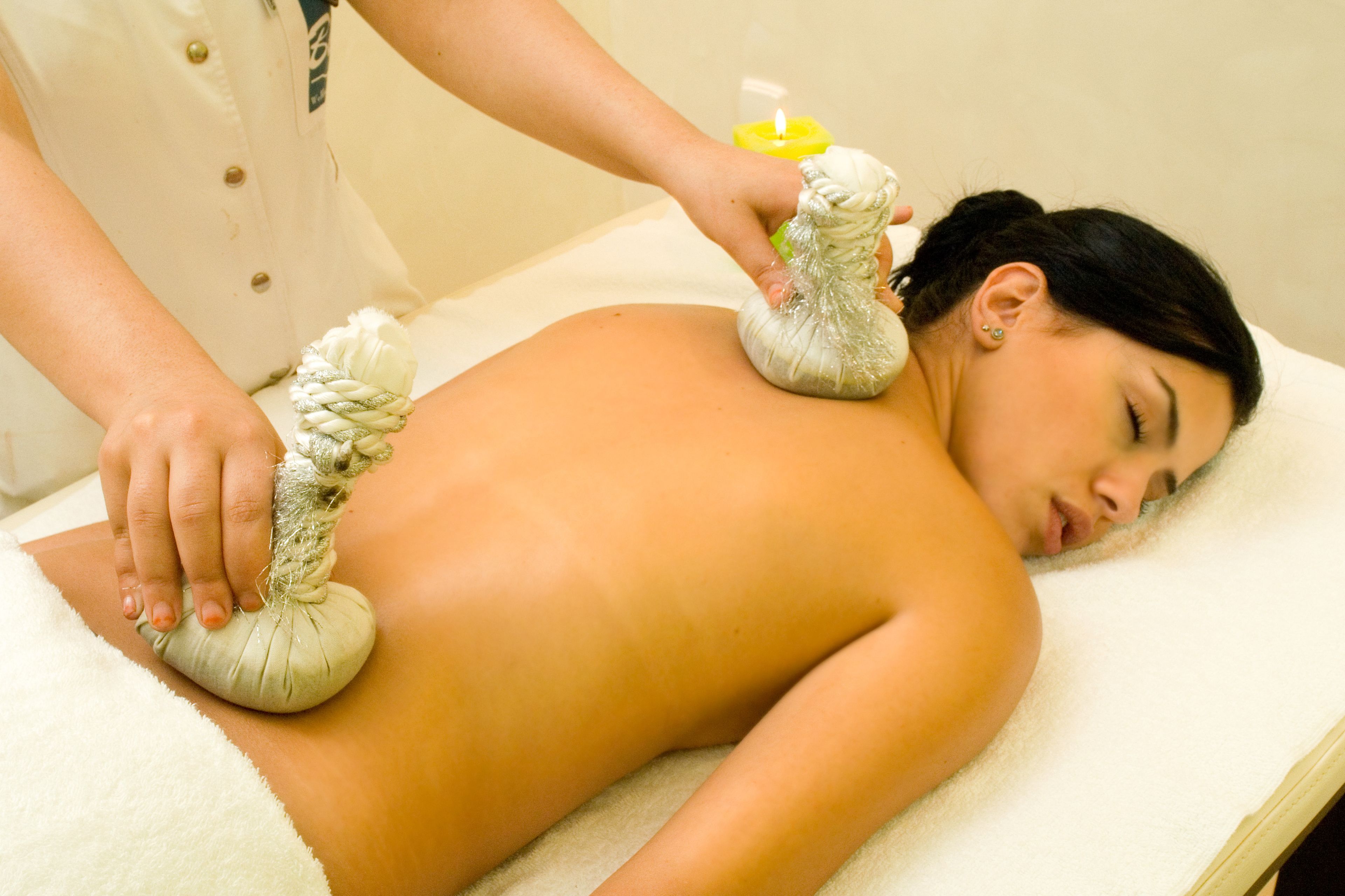 A person receiving a massage with a towel and a yellow bottle on a massage table.