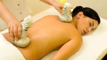 A person receiving a massage with a towel and a yellow bottle on a massage table.