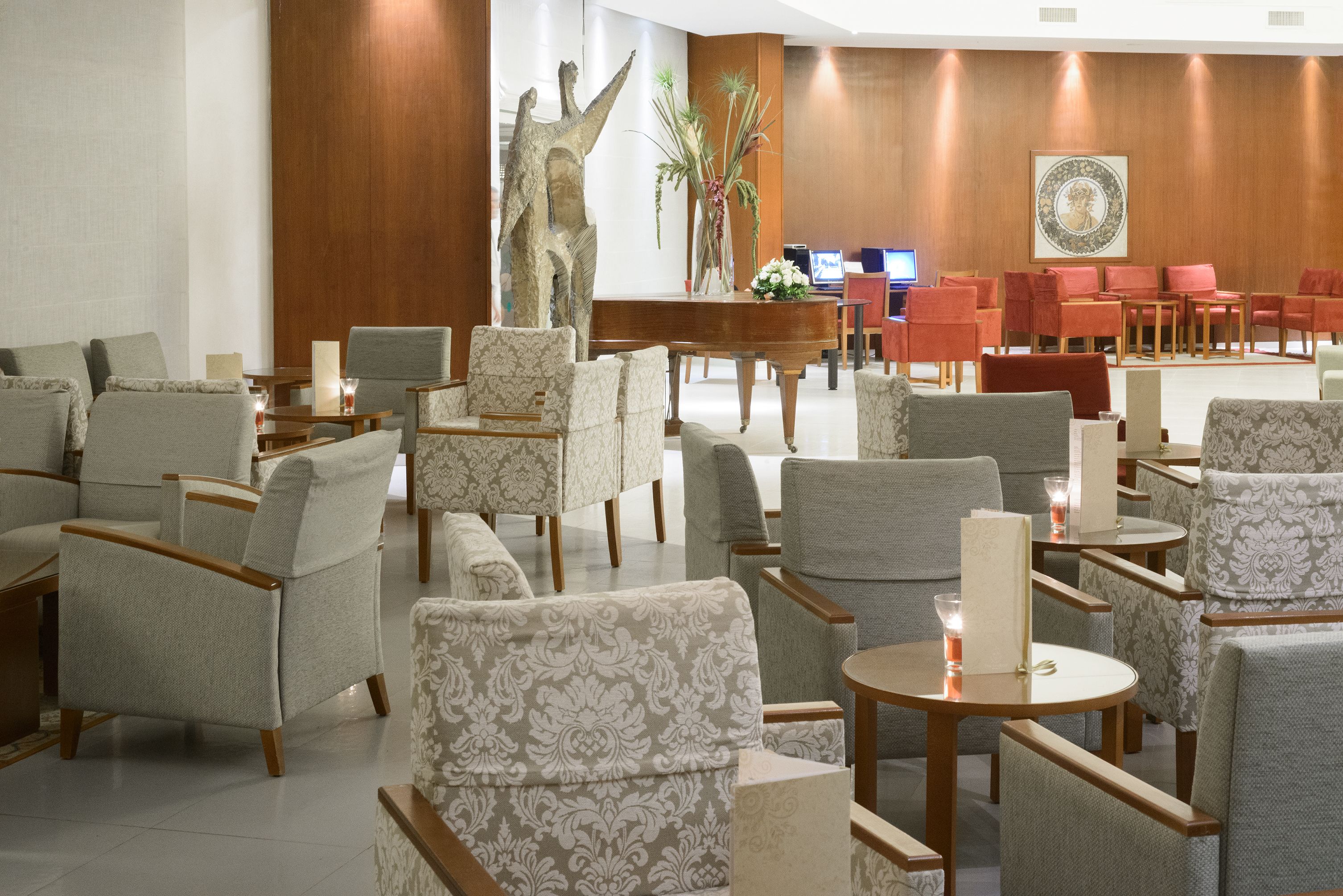 A hotel lobby with multiple seating areas, a reception desk, and a piano.