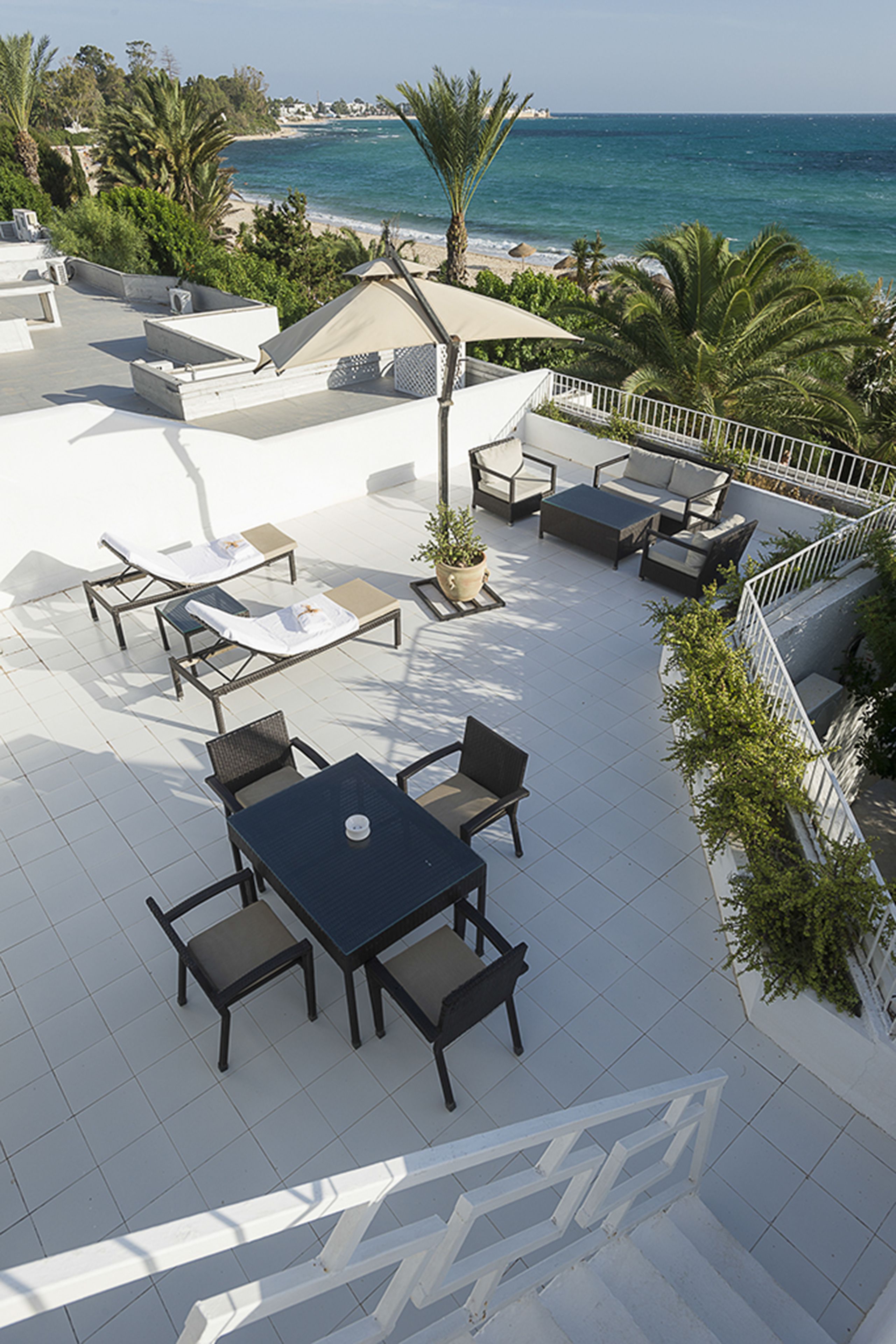 A rooftop terrace with outdoor seating, a table, and a view of the sea.
