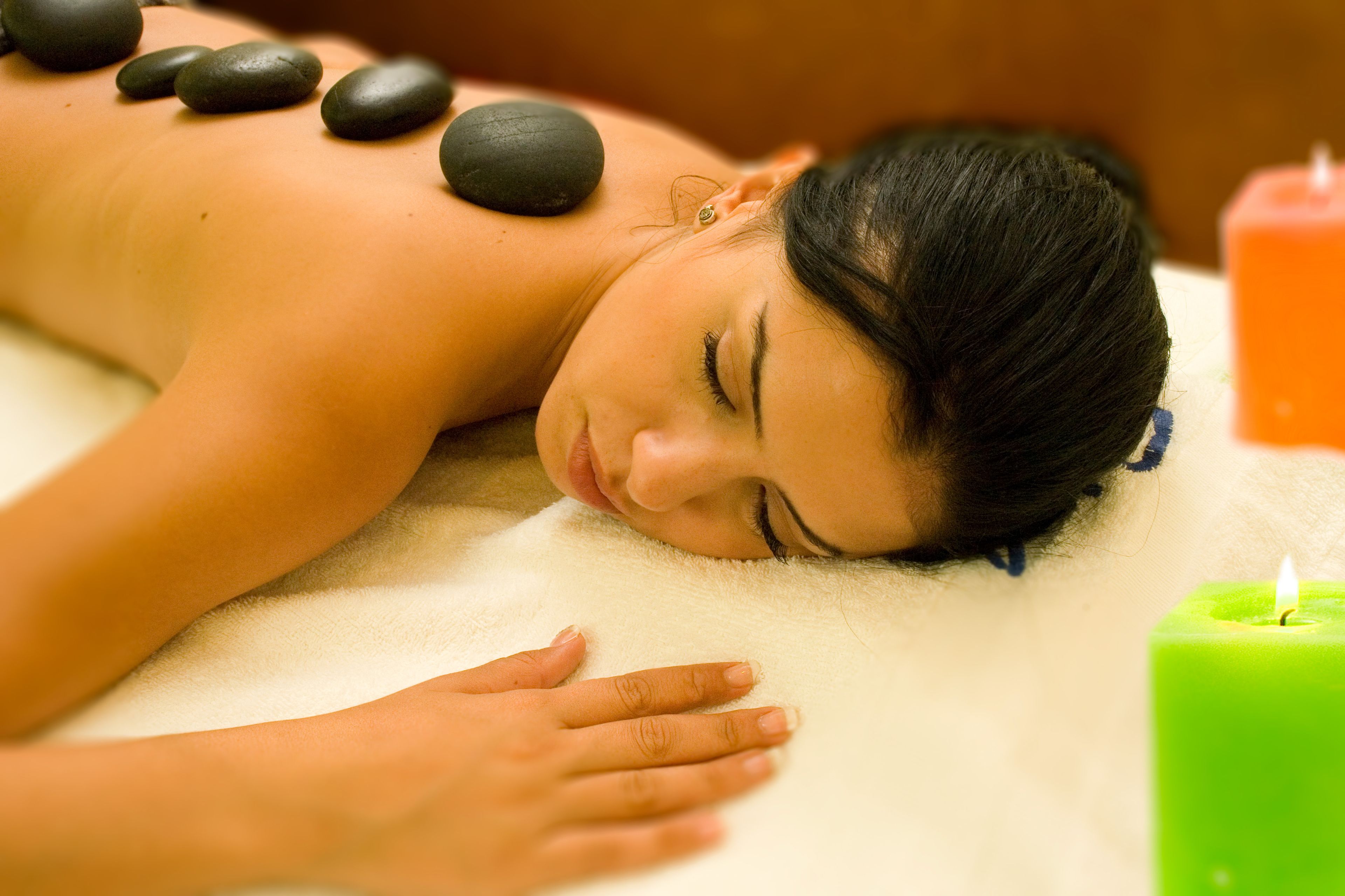 A person receiving a massage with stones and a lit candle.