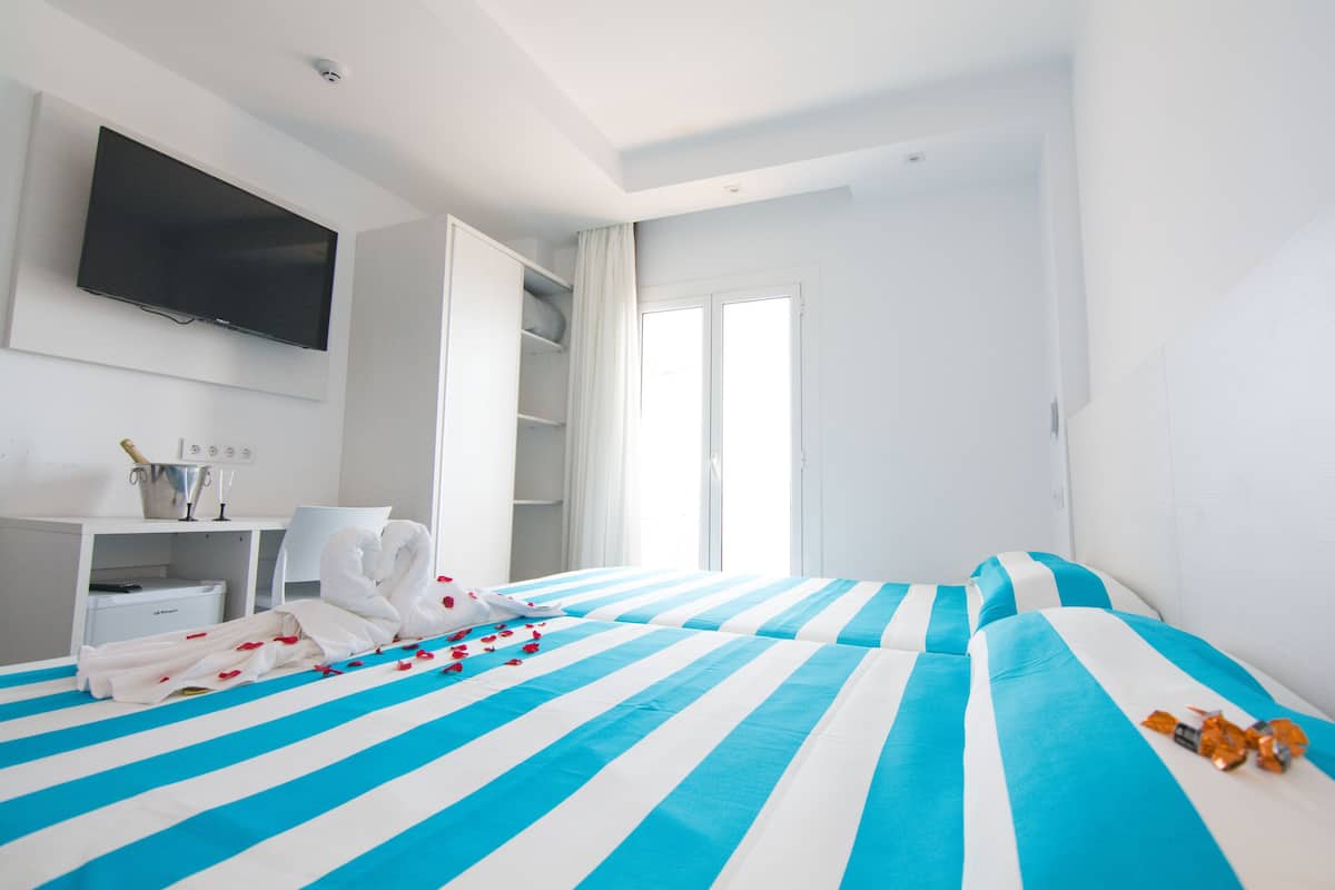 Habitación de hotel con una cama grande, un televisor montado en la pared, un escritorio con silla y un armario.