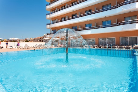 Una piscina al aire libre, sombrillas, sillones reclinables de piscina