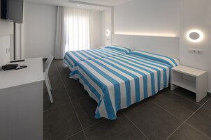 A modern hotel room with a large bed, a desk, and a TV.