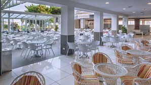 Un amplio comedor interior con varias mesas y sillas, ventanas grandes y vistas al exterior.