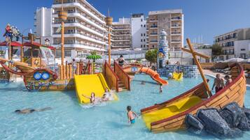 A water park with slides and play structures, surrounded by multi-story buildings.